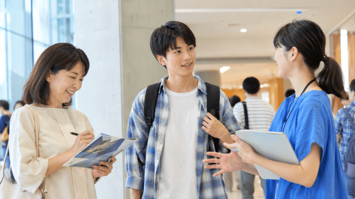 オープンキャンパスで在学生に質問する高校生とメモを取る保護者