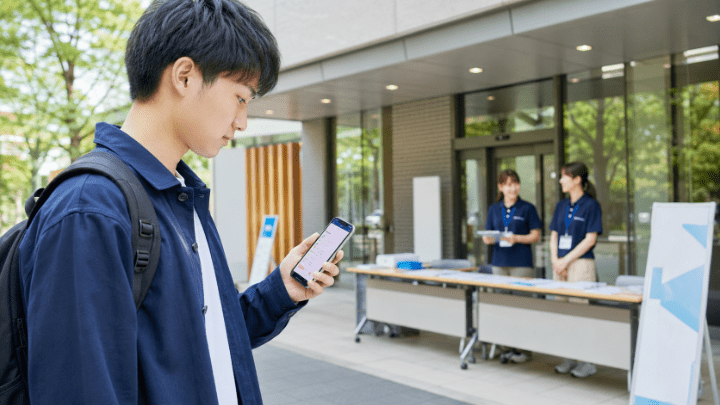 オープンキャンパスの受付前に予約内容を確認する高校生
